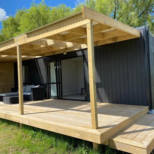 a deck with a pergola on top of a house at Tiny Home Farm Stay Retreat in Hikutaia