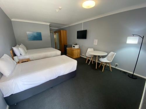 a hotel room with two beds and a table and chairs at Old Maitland Inn - Rutherford in Maitland