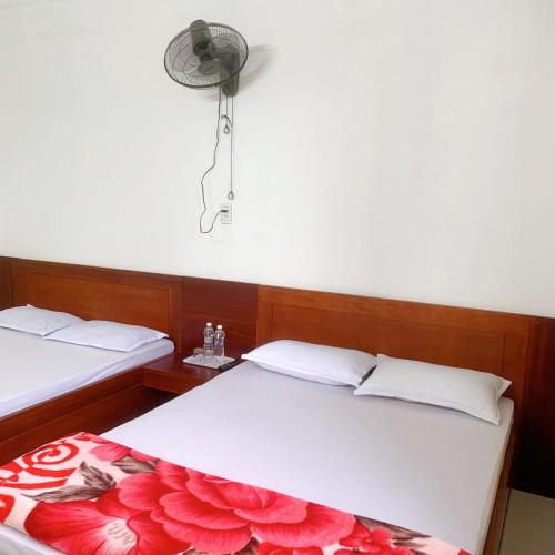 a bedroom with two beds and a lamp on the wall at Hotel Thanh Minh in Châu Làng Chánh