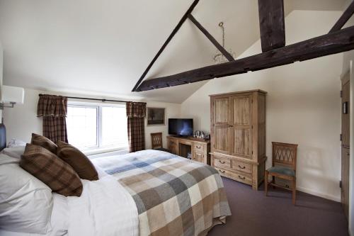 a bedroom with a bed and a tv and a window at The Carpenters Arms in Thirsk