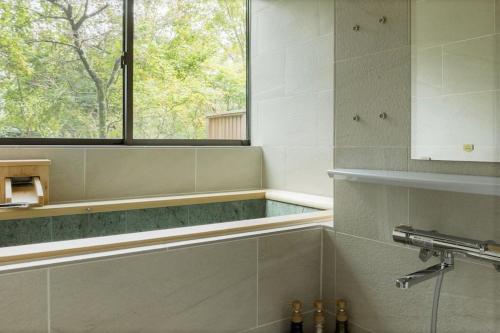 雅・小涌谷　温泉別荘　Miyabi Kowakudani Hopspring Villa في Ashinoyu: حمام مع حوض استحمام ونافذة