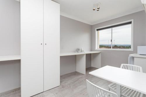 a white kitchen with a white table and chairs at Burleigh Gold Coast Motel in Gold Coast