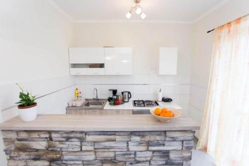 a white kitchen with a bowl of oranges on a counter at Apartment Antea - private parking & garden in Čilipi