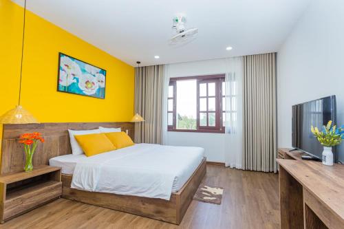 um quarto com uma cama e uma parede amarela em SOLEIL BOUTIQUE em Hue