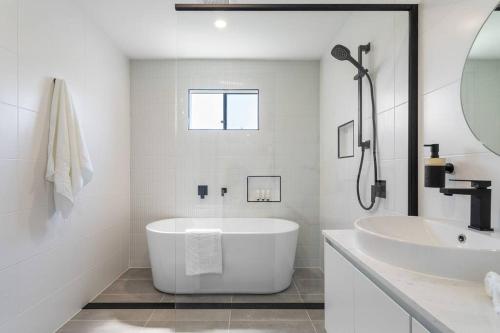 a white bathroom with a tub and a sink at Beauty By The Water in Chittaway Point