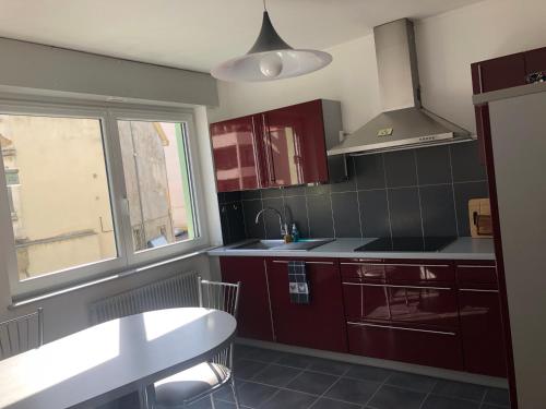 kuchnia z czerwonymi szafkami, umywalką i oknem w obiekcie Appartement l'œil de Colmar w mieście Colmar