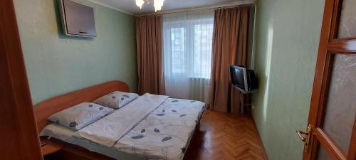 a small bedroom with a bed and a television at Apartment on Patriarkha Mstyslava Skrypnyka Street in Kyiv