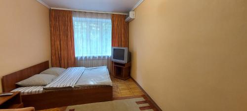 - une petite chambre avec un lit et une télévision dans l'établissement Воздухофлотский проспект, à Kiev