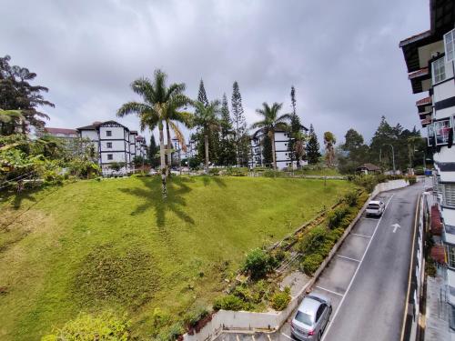 a green hill with cars parked on the side of a road at A ONE Holiday Apartment in Tanah Rata