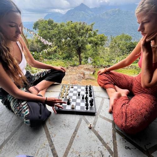 two women sitting on the ground playing chess at Dream Ville in Ella