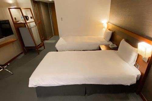 a hotel room with two beds and a television at Guide Hotel Hsinchu Zhongyang in Hsinchu City