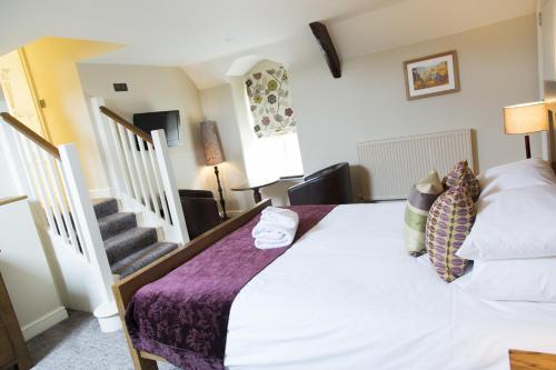 a bedroom with a bed, chair, and nightstand at The Colesbourne Inn in Colesbourne
