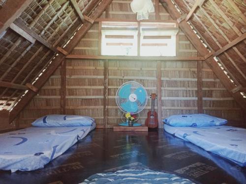 an attic room with two beds and a fan at Titaays Surfers Inn in Baras