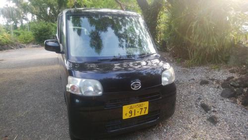 un camion noir garé sur le côté d'une route dans l'établissement 八丈島メープルハウス, à Hachijō