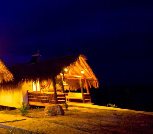 a building with a thatch roof at night at Amazonia Bungalow in Máncora