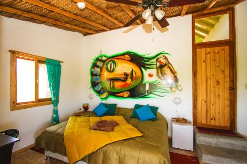 a bedroom with a bed with a painting on the wall at Amazonia Bungalow in Máncora