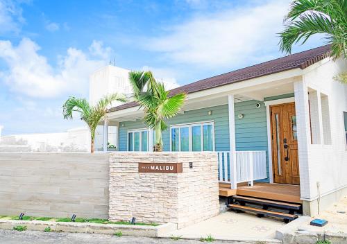 une maison bleue avec une véranda et des palmiers dans l'établissement Villa Malibu Palm Springs Miyakojima Resort, à Île Miyako