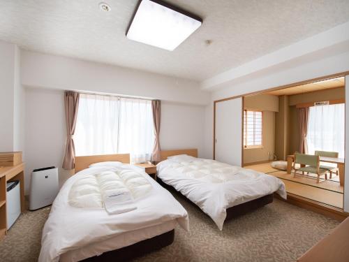 Habitación de hotel con 2 camas y ventana en Chateraise Lodge Kasugai en Fuefuki
