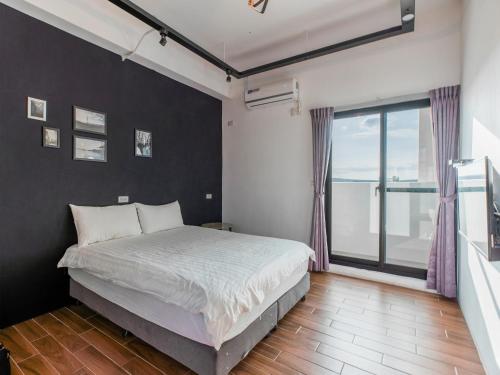 a bedroom with a bed and a large window at 25Inn Hengchun Kenting in Nanwan
