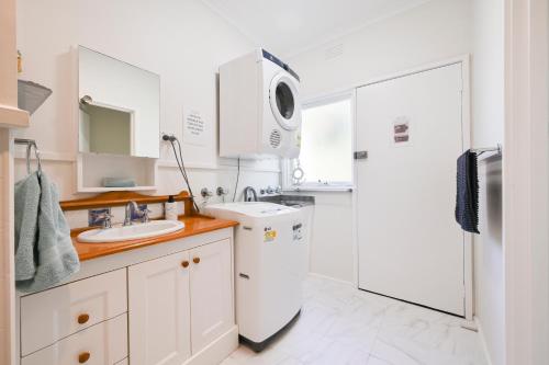 a white kitchen with a sink and a refrigerator at Beach Cottage. 100m to the beach 9minutes to Hot Springs. Pet Friendly in Capel Sound