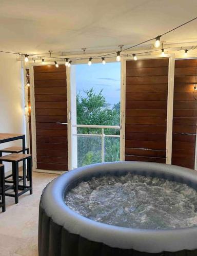 eine große Badewanne in einem Zimmer mit einem großen Fenster in der Unterkunft L'appartement du bonheur l Saint-Gilles les Bains in Grand Fond