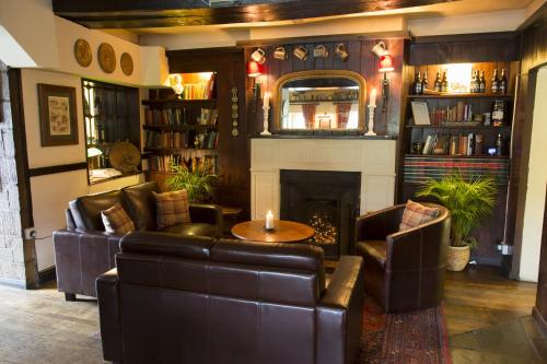 een woonkamer met lederen meubels en een open haard bij The Colesbourne Inn in Colesbourne