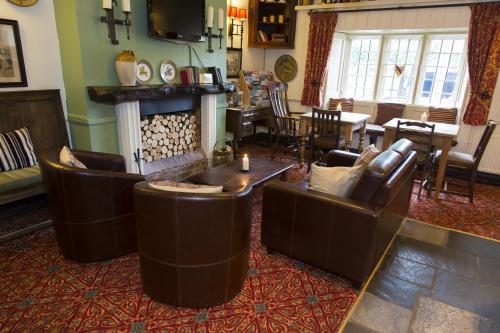 a living room with leather furniture and a fireplace at The Colesbourne Inn in Colesbourne