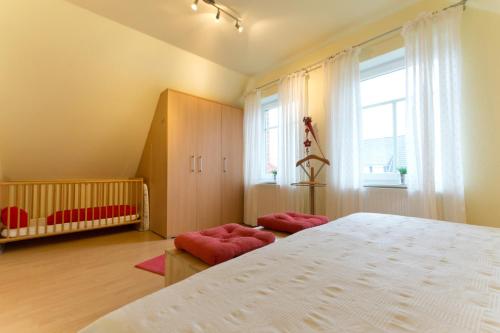 a bedroom with a large white bed and a crib at Ferienhaus Sabine Norddeich in Norddeich