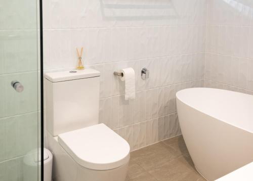 a white bathroom with a toilet and a sink at Number 2 On The Beach | Beautiful Beachfront Villa in Port Douglas