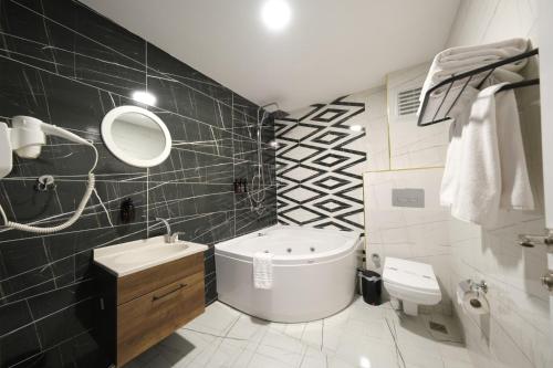 a bathroom with a tub and a sink and a toilet at Eniza Hotel in Mersin