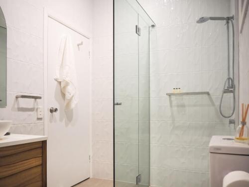 a glass shower door in a bathroom with a toilet at Number 2 On The Beach | Beautiful Beachfront Villa in Port Douglas