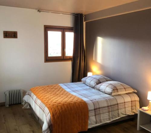 ein Schlafzimmer mit einem Bett mit einer orangefarbenen Decke und einem Fenster in der Unterkunft Chez Mario 