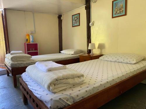 a room with three beds in a room at Mile 36 Lodge in Kundasang