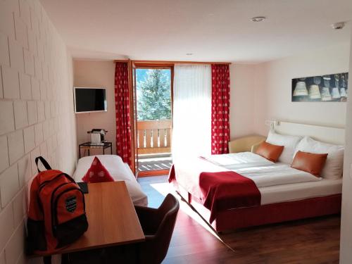 a bedroom with a bed and a table and a window at Hotel Restaurant Knobelboden in Oberterzen