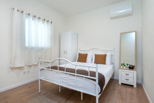 een slaapkamer met een wit bed en een spiegel bij Melony Apartments Yam Suf Street in Eilat