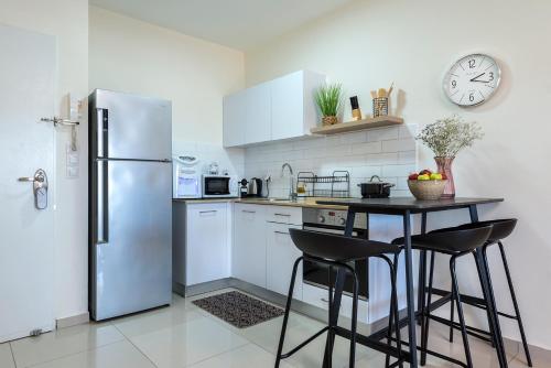 een keuken met een koelkast en een tafel met krukken bij Melony Apartments Yam Suf Street in Eilat