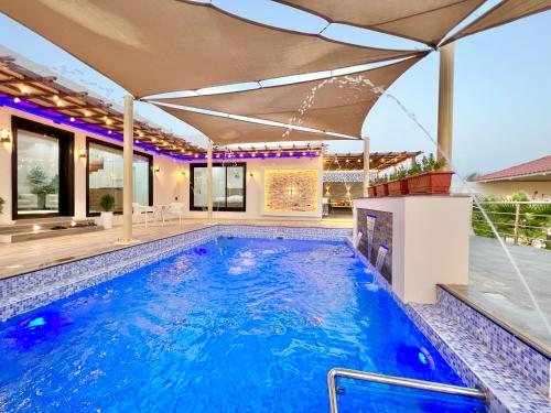 a swimming pool in a house with an umbrella at AlDana Resort & Hotels in Barka