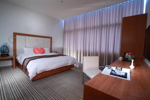 um quarto de hotel com uma cama com uma almofada vermelha em Yoai Hotel em Yilan City