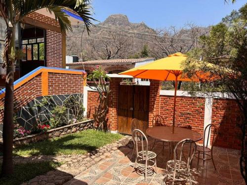 Un patio con una sombrilla y una mesa y sillas. en Azomalli, en Tepoztlán