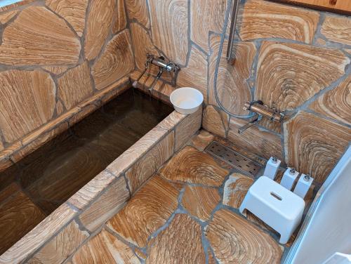 La petite salle de bains est pourvue d'une douche et d'un mur en pierre. dans l'établissement お宿でん吉, à Minami Aso