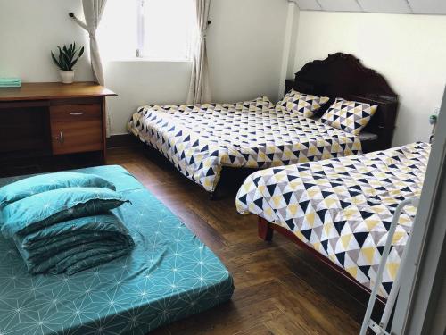 a bedroom with two beds and a table and a bedskirts at NHỚ House IV in Da Lat