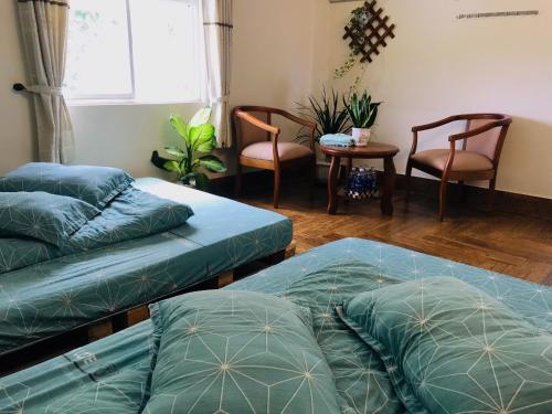 two beds in a room with chairs and a table at NHỚ House IV in Da Lat