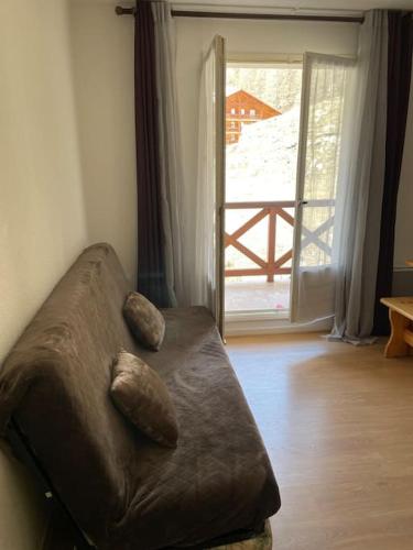 a brown couch with two pillows sitting in a living room at Allos, logement pieds des pistes, à 10 minutes de la base de loisirs in Allos