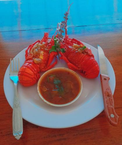 a lobster on a plate with a bowl of soup at Titaays Surfers Inn in Baras