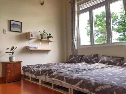 a bedroom with a bed and a large window at NHỚ House IV in Da Lat