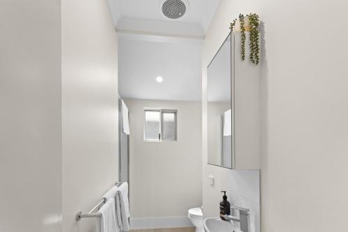 a white bathroom with a toilet and a mirror at Dragonfly Abode, 2BR Villa in Cable Beach