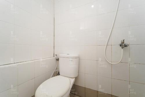 a bathroom with a toilet with a hose on the wall at RedLiving Apartemen Bassura City - Gracefull Rooms Tower Dahlia in Jakarta