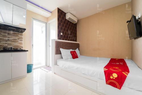 a bedroom with a bed with a red blanket on it at RedLiving Apartemen Bassura City - Gracefull Rooms Tower Dahlia in Jakarta