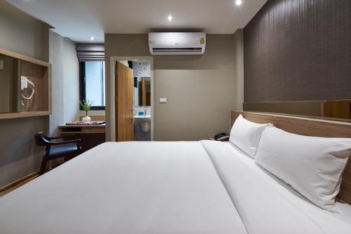 a bedroom with a large white bed and a desk at Almas Hotel Bangkok in Bangkok