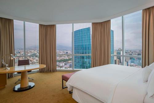 um quarto de hotel com uma cama, uma secretária e janelas em The Westin Lima Hotel & Convention Center em Lima